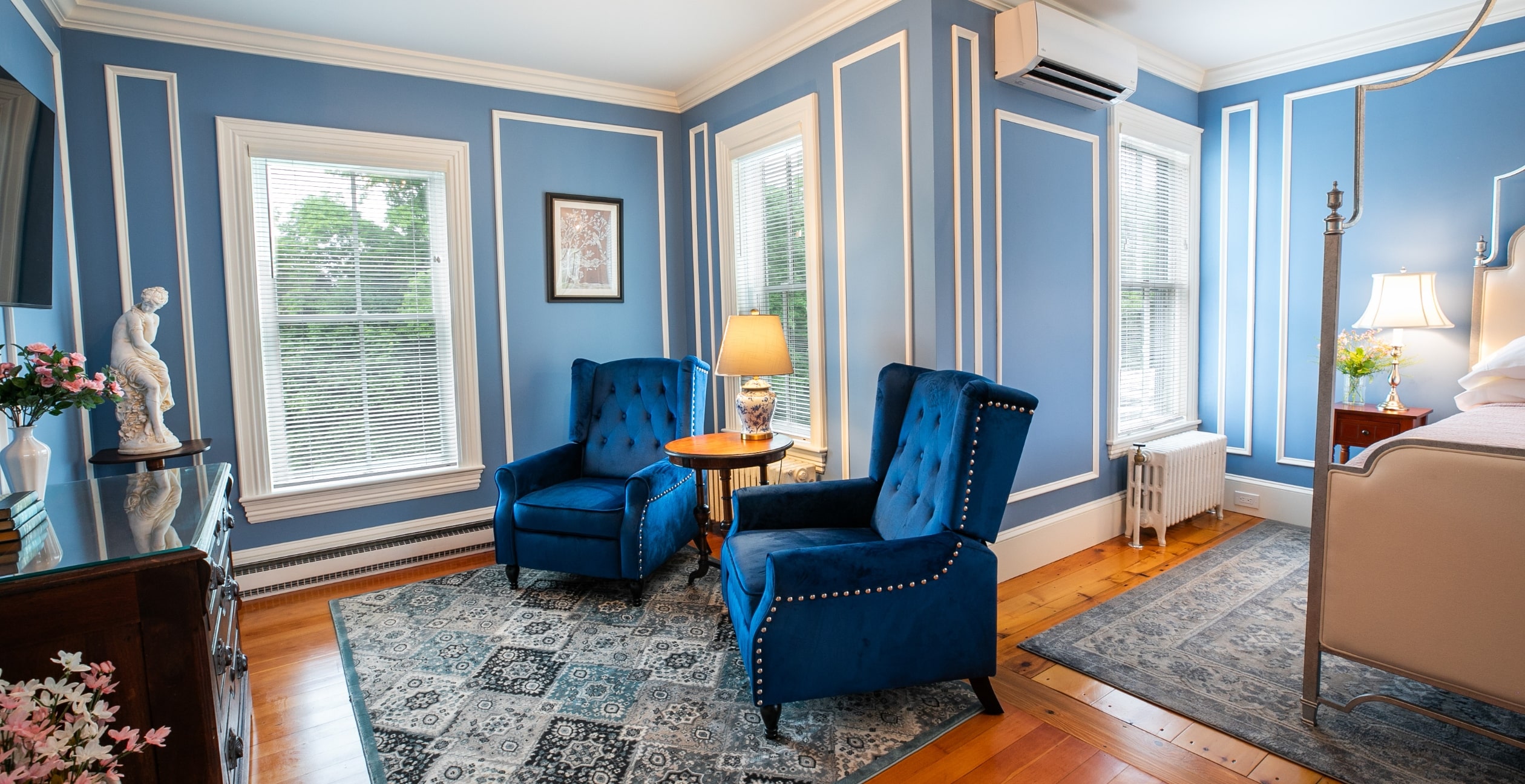 sitting area with two blue chairs and a queen bed