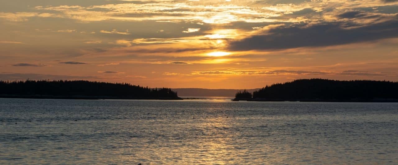 a brilliant golden orange-red sunset over penobscot bay in midcoast maine